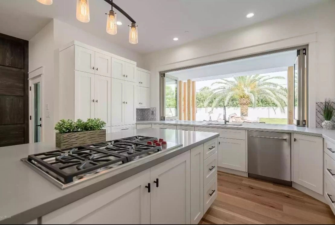 The pass-through window opened above the sink run, with the island cooktop in the foreground